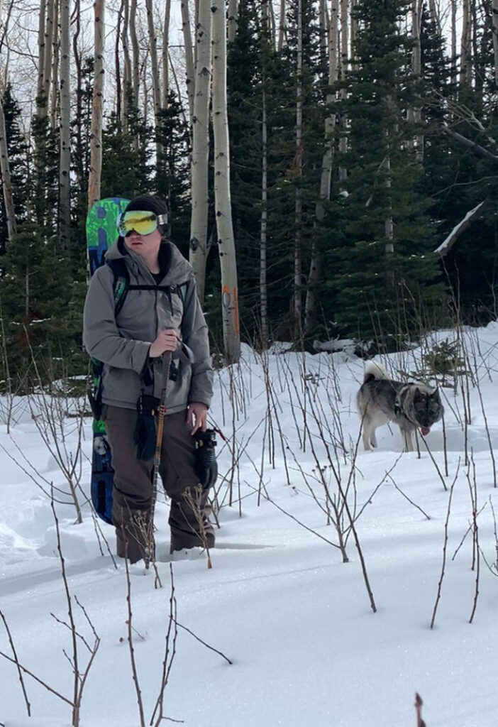 Max hiking with his snowboard and dog